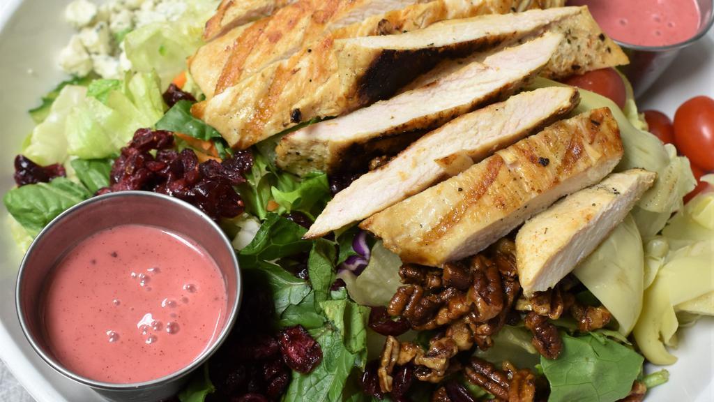 The Pin Up Girl · Fresh greens topped with cherry tomatoes, artichoke hearts, sweet pecans, dried cranberries, blue cheese crumbles, and fresh cucumbers. Served with balsamic raspberry vinaigrette and finished off with the grilled chicken.