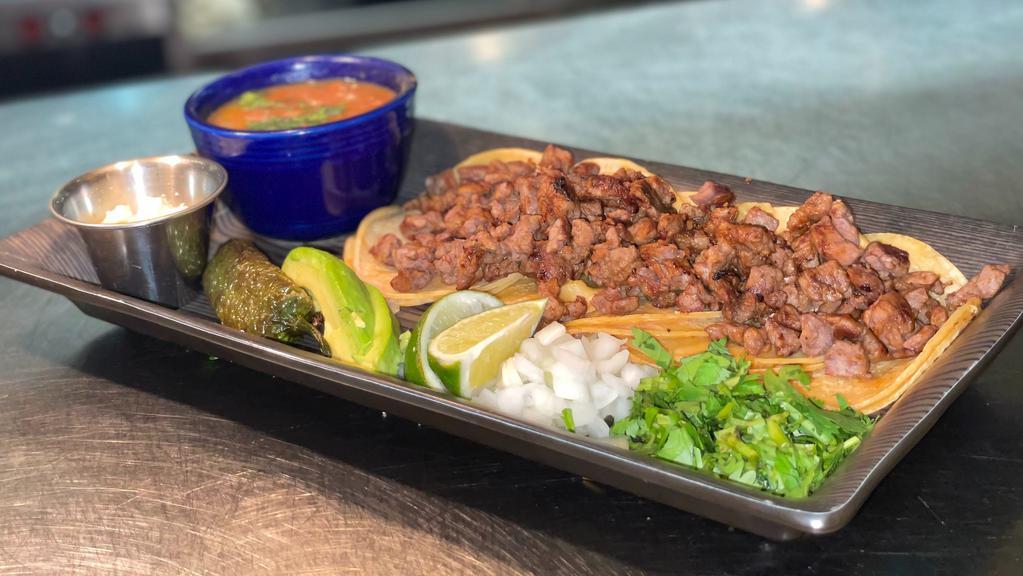 Street Tacos · Four minicorn tortillas filled with tender steak pieces  served with cilantro, fresh onions, a chile toreado, charro beans, queso fresco and avocado.
