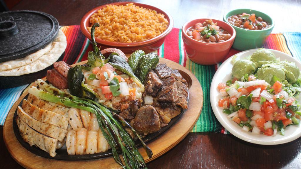 Parrillada · Marinated beef and chicken fajitas, country sausage, pork carnitas, grilled shrimp and one chorizo and cheese stuffed poblano pepper, all over a bed of grilled onions and bell peppers. Served with pico de gallo and six tortillas. Serves 3-4.