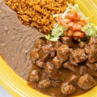 Carne Guisada · Savory beef tips cooked and simmered in our familia's special gravy. Served with refried bea...