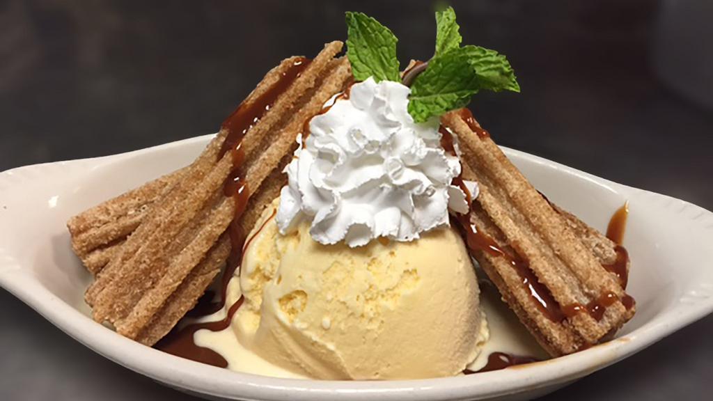 Churros With Ice Cream · Two churros with a heaping scoop of vanilla ice cream.