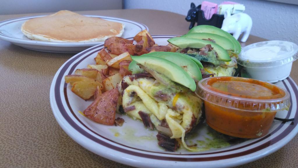 Spicy Poblano Country Omelette · Shredded beef, roasted poblanos, roasted onions, cheese, spicy poblano sauce topped with avocado and side of salsa and sour cream.