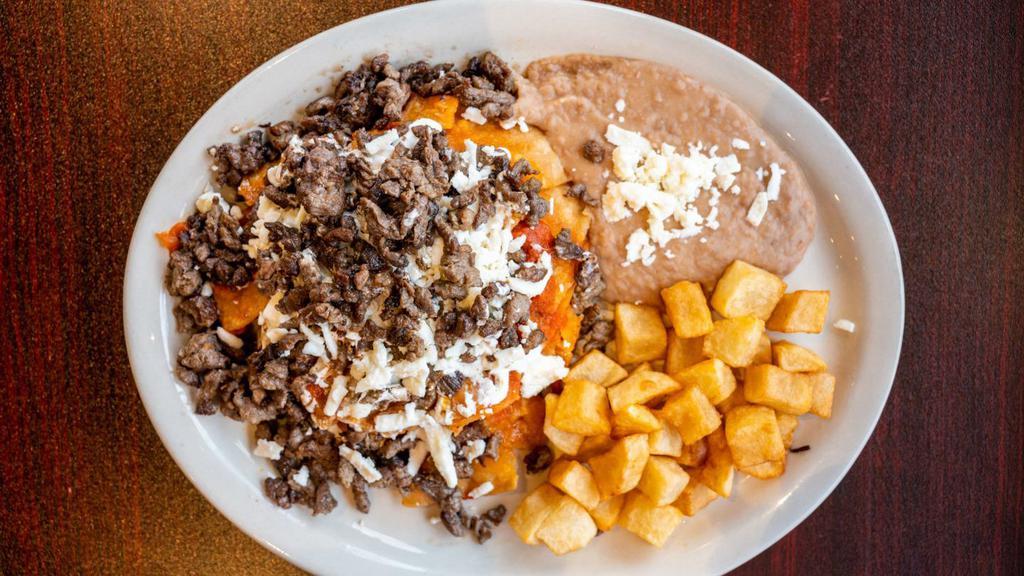 Chilaquiles With Asada · TORTILLA CHIPS WITH  SAUCE OF YOUR CHOICE, QUESO FRESCO, SOUR CREAM AND CARNE ASADA ON TOP, SERVED WITH REFRIED BEANS, BREAKFAST POTATOES AND TWO TORTILLAS ON THE SIDE .