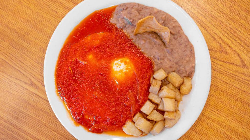 Huevos Rancheros · THREE EGGS WITH RANCHERO SAUCE ON TOP, SERVED WITH BREAKFAST POTATOES, REFRIED BEANS AND TWO TORTILLAS ON THE SIDE.