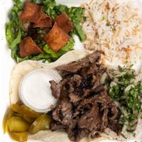 Shawarma Beef Platter · A platter of beef shawarma on bread, pickles, and traditional tahini sauce served with rice ...