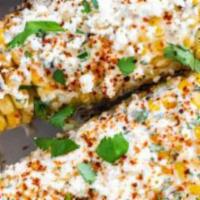 Elote On The Cob · Two halves of a cob topped with homemade elote with cotija cheese.