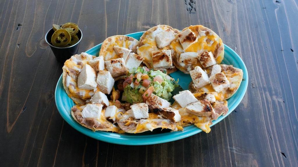 Chicken Nacho · Mesquite grilled fajita chicken atop refried beans & mixed cheese melted to perfection. Served with a side of guacamole, pico de gallo & jalapeños.