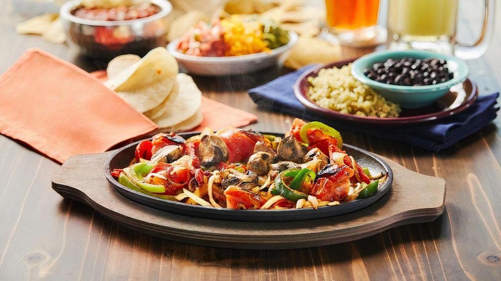 Veggie Fajitas · Vegetarian. A sizzling skillet of sautéed mushroom, tomatoes, poblano & bell peppers & onions. Served with poblano lime rice & black beans.