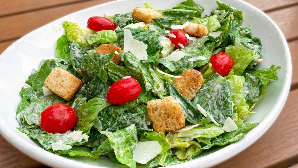 Caesar · Romaine lettuce tossed in Caesar dressing, topped with shaved parmigiano cheese.