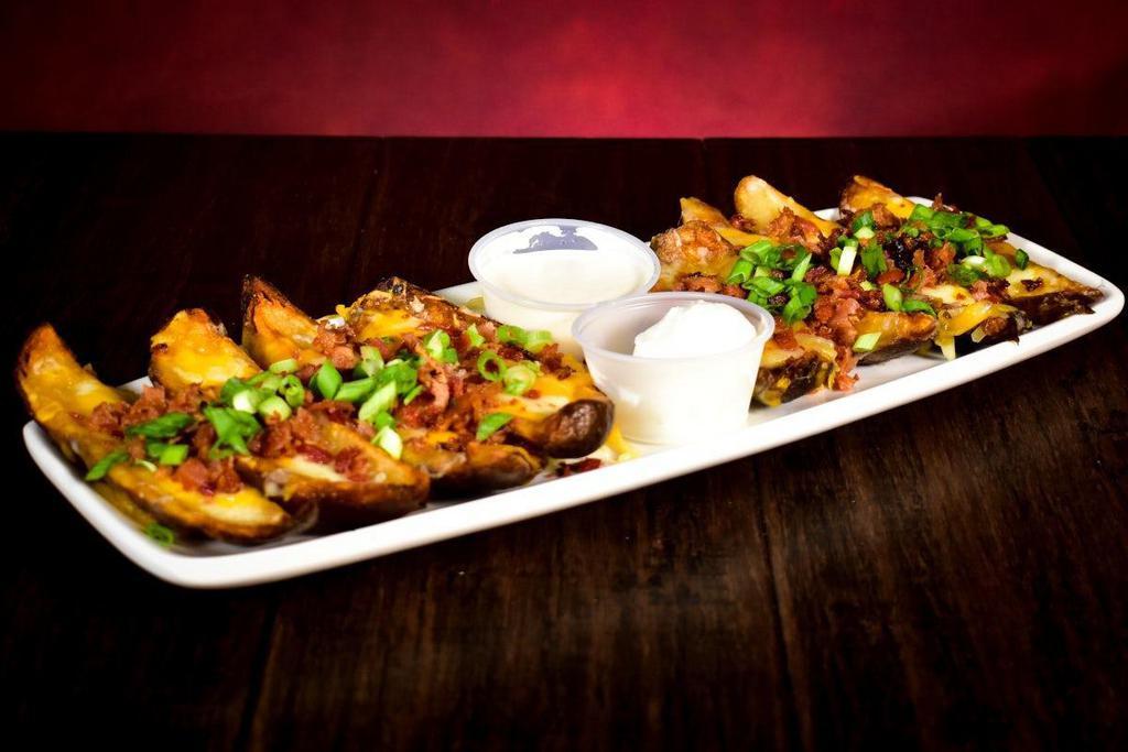 Potato Skins · Made in house and topped with melted cheese, bacon pieces, & green onions. Served with sour cream & Peppercorn Ranch dressing.