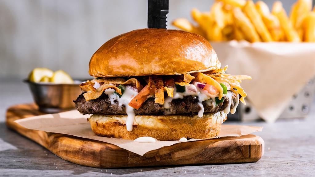 Queso Burger (Classic) · White queso, crunchy tortilla strips, pico. 950 cal. **Disclaimer: may be cooked to order. Consuming raw or undercooked meats, poultry, seafood, shellfish, or eggs may increase your risk of foodborne illness, especially if you have certain medical conditions.**