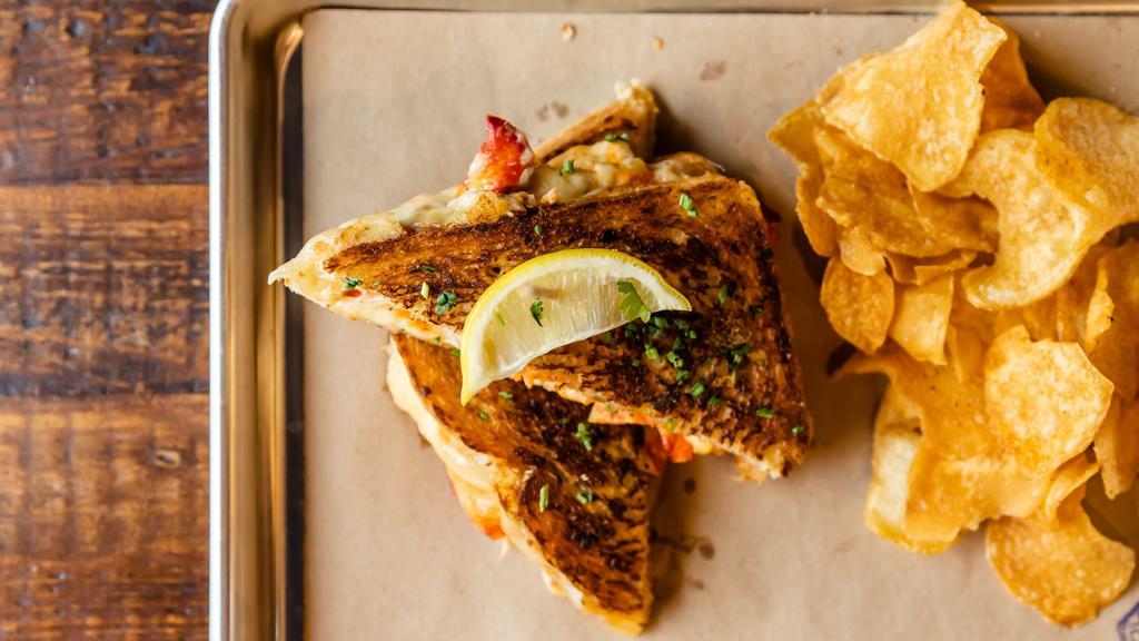 Lobster Grilled Cheese · Lobster, Sriracha, Crab Queso, Sourdough Bread. Served with pickles and chips
