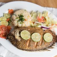 Mojarra Frita · A fried whole Tilapia fish with rice and lettuce topped with diced tomatoes along with limes...