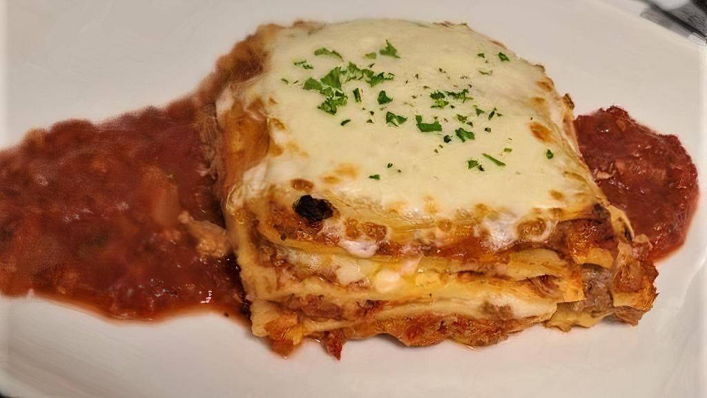 Lasagna Bolognese · Layers of meat sauce, béchamel, parmesan, and mozzarella cheeses, baked until bubbly and golden and served on a bed of savory marinara.