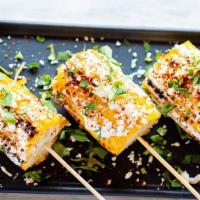 Street Corn · Three corn roasted on the grill topped with mayonnaise, queso fresco, cilantro, and tajin.