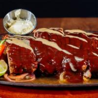 Baby Back Ribs · Oven cooked to perfection, smothered in bbq sauce and served on a bed of grilled onions.