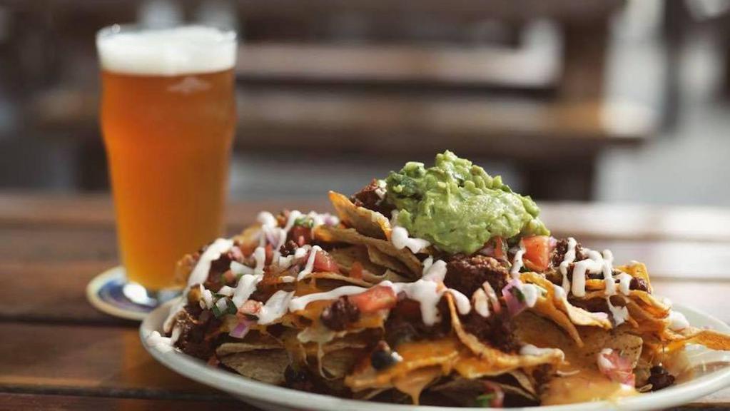 Nacho Libre · Tostada chips topped with queso, spiced beef, pico de gallo, cheddar cheese, black beans, chipotle sour cream, and guacamole.