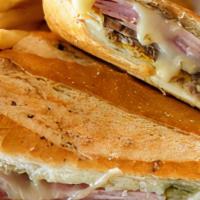 Cuban Sandwich (Sandwich Cubano) · Roast pork is layered with ham, Swiss cheese, pickles, mayo and yellow mustard in toasted Cu...