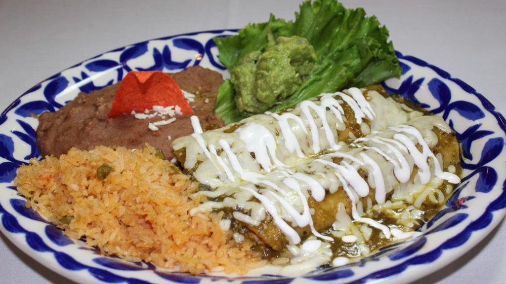Enchiladas Verdes · Two shredded chicken enchiladas topped with tomatillo salsa, Monterey jack cheese & a light drizzle of sour cream, served with guacamole, frijoles refritos & Spanish rice.