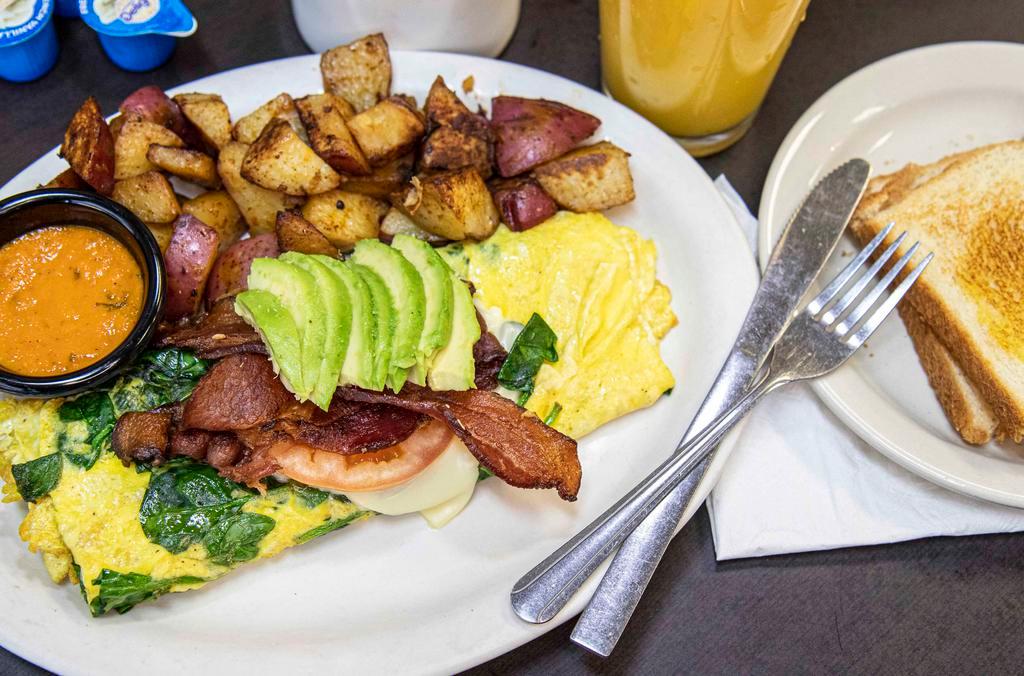 Blt Omelette · Three eggs omelette style with spinach and swiss cheese; topped with two sliced tomatoes, two strips of bacon, and sliced avocado, and served with red potatoes or hash browns toast or a biscuit.