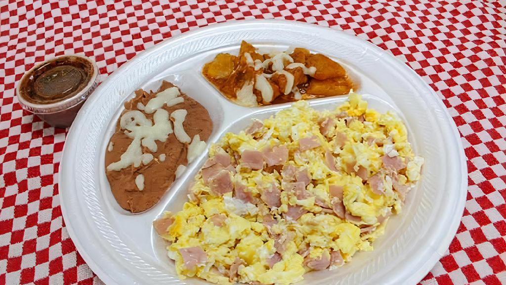 Huevos Con Jamon · Tres huevos revueltos con jamon acompañados con frijoles, papas y tortillas. 
Three eggs scrambled with ham, served with beans, potatoes, and tortillas.