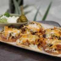 Nachos · White corn tortilla chips topped with refried beans and grated cheeses. Served with guacamol...