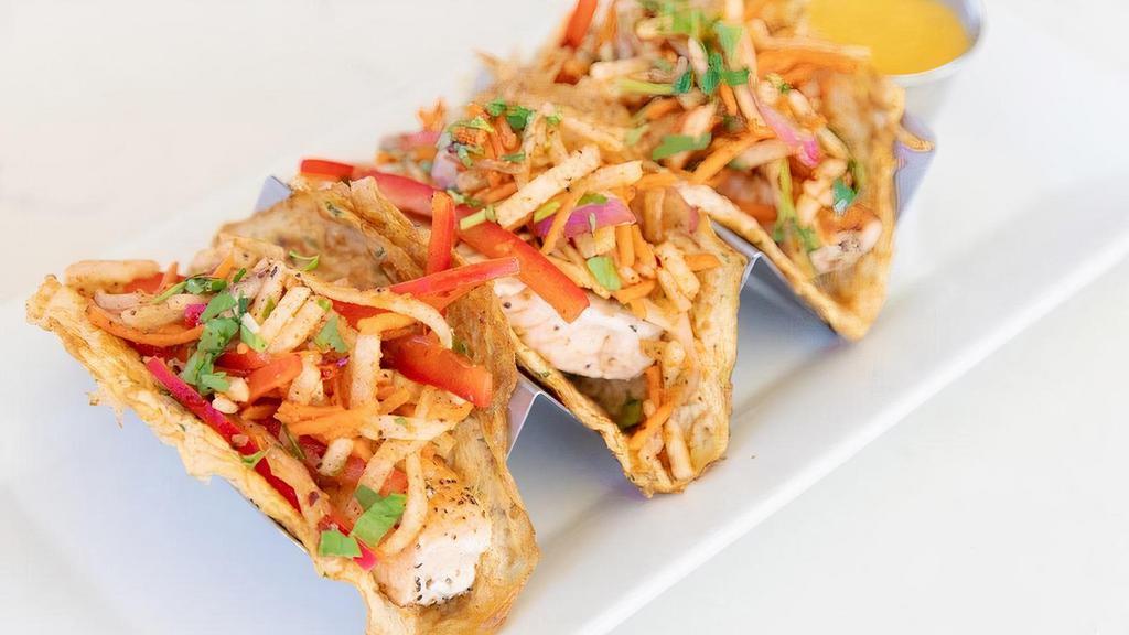 Paleo Rainbow Slaw Salmon Tacos · Pan-seared sustainably sourced salmon topped with our rainbow slaw of jicama, red onion, shredded carrots, red bell pepper & cilantro tossed together with spices & house vinaigrette, all atop house-made paleo tortillas & served with our mango habanero sauce on the side