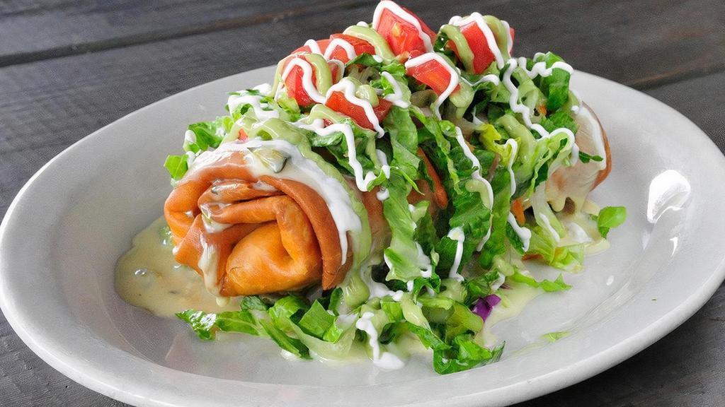 The Bad Daddy Chimi · Giant flour tortilla stuffed with fajita steak and cheese, lightly fried, smothered in queso, topped with lettuce, tomatoes, sour cream and avocado ranch.