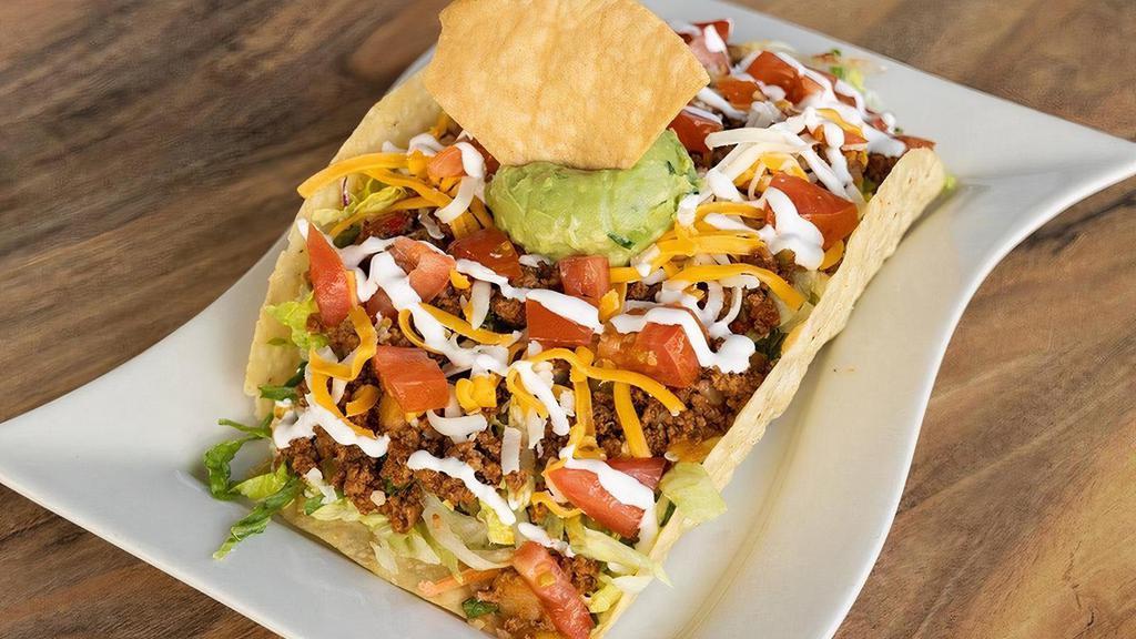 Taco Salad · Giant crispy taco shell stuffed with chopped lettuce, tomatoes, grated cheese, guacamole & sour cream -- choice of meat.
