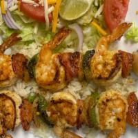 Shrimp Brochetas · Grilled shrimp with onions & pepper skewer over a bed of rice served with salad