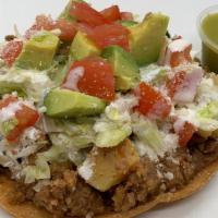 Tostada Picadillo · Home-made Picadillo (ground beef with potatoes) served over a corn tostada with, beans, lett...