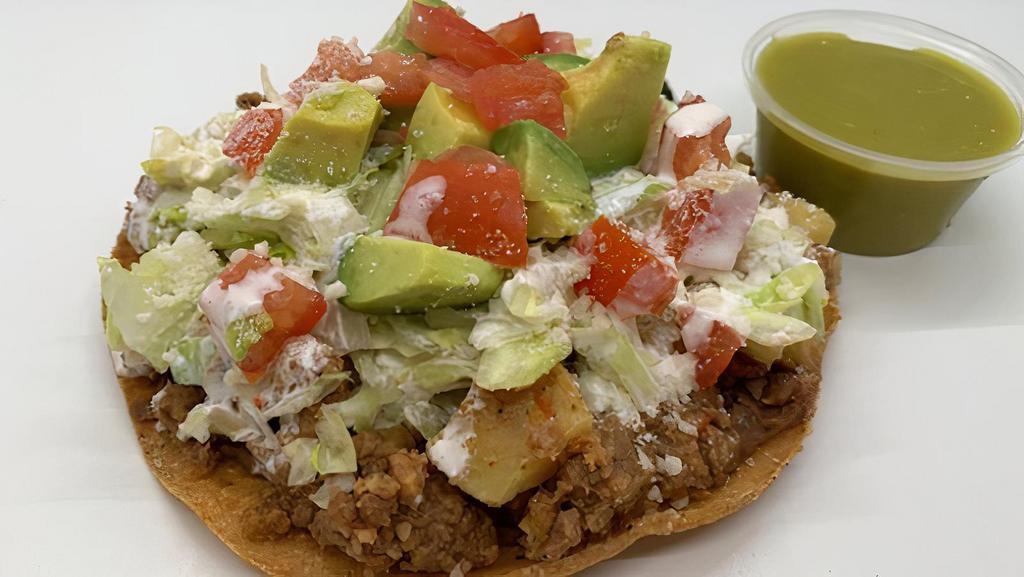 Tostada Picadillo · Home-made Picadillo (ground beef with potatoes) served over a corn tostada with, beans, lettuce, sour cream, tomato, cotija cheese, and avocado with your choice of hot sauce.