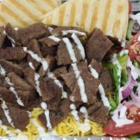 Gyro Over Rice · Beef gyro served over rice with salad and sauces.