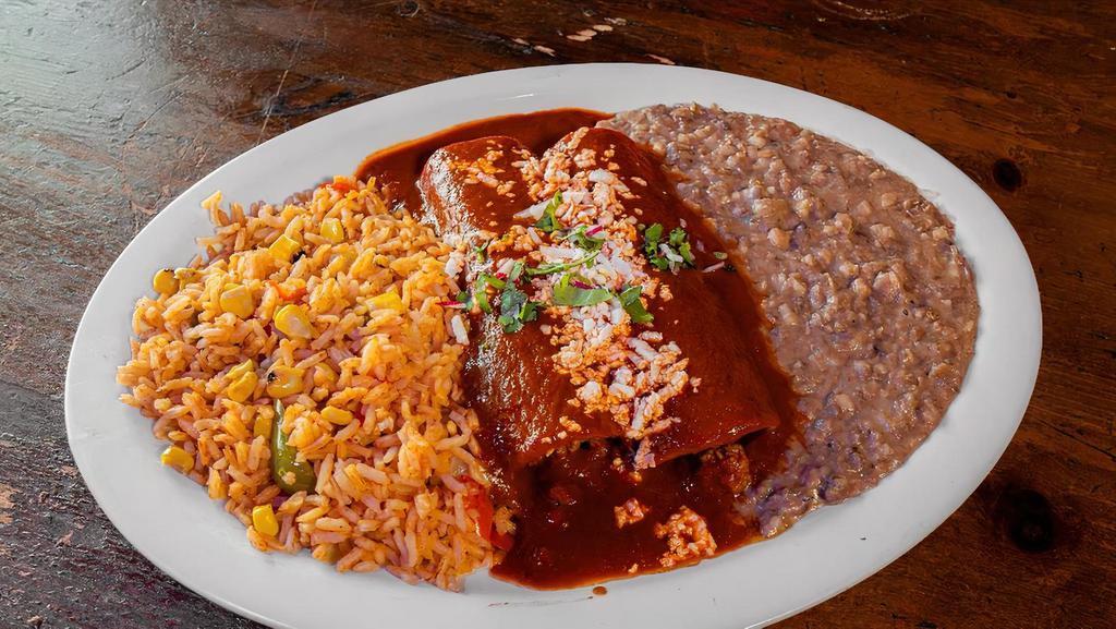 Enchiladas Rojas · Enchiladas  covered with ancho-guajillo sauce. Filled with your choice of picadillo or cheese, and covered with crema and queso fresco served with Mexican rice and refried beans.