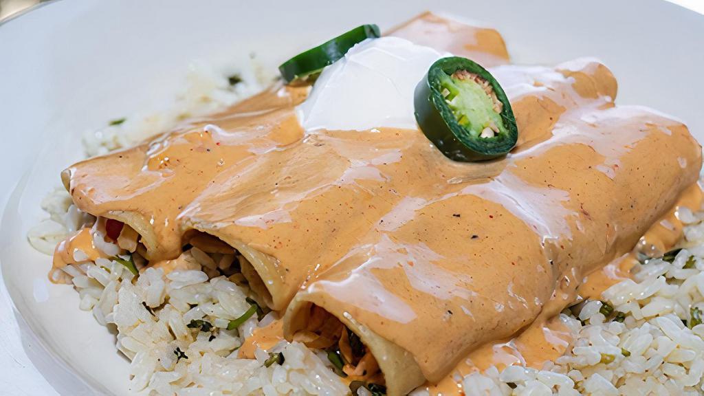 Sw Seafood Enchiladas · Corn tortillas stuffed with Atlantic salmon, shrimp, wild Alaska Pollock, peppers, onions, and cheddar-jack cheese, topped with a light cream sauce, sour cream, and jalapeño. Served on a bed of cilantro lime rice.