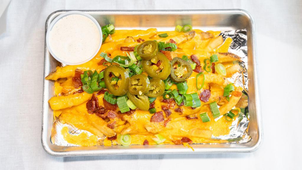 Side Of Loaded Fries · Side order of fries smothered in cheddar cheese, hickory smoked bacon, pickled jalapeno and green onions. Served with house made ranch.