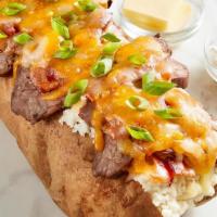 Loaded Steak Spud · Seared sirloin steak, applewood smoked bacon, cheddar jack cheese, and green onion in a gian...