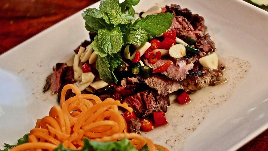Tiger Cry · Rib-eye steak grilled with fresh garlic, thai chili pepper, lime juice, and fish sauce, served with cucumber and basil on the side.