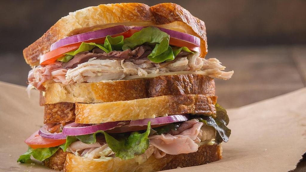 Famous | Club · Slow-roasted hand-pulled turkey, roast. beef, ham, Kneaders sauce, provolone cheese, lettuce, tomatoes, red onions, salt & pepper. Served on French Country Sourdough.