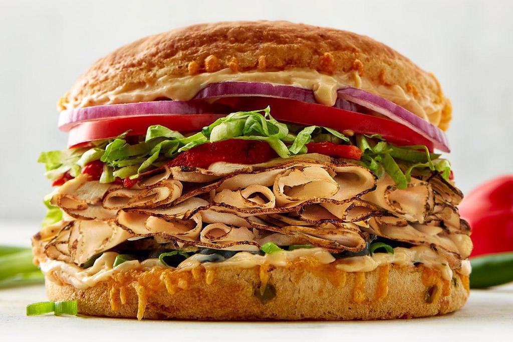 Fiesta-Style Sandwich · CHOICE OF: smoked turkey | ham | chicken | roast beef. COMES WITH: cheese | olives | roasted red peppers | lettuce | red & green onions |tomato | chipotle mayo | jalapeño cheese bun.