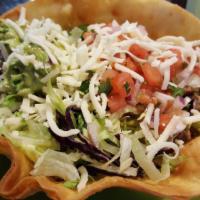 Taco Salad · Romaine lettuce, cheddar cheese, fresh tomatoes, bacon, sour cream and ground beef, served i...