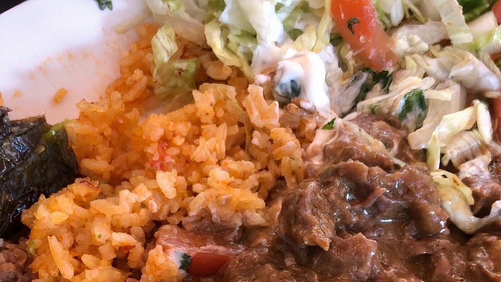 #20 Carne Guisada Plate · Slow cooked beef tips in a Mexican stewed gravy, served with rice and beans and a guac salad.