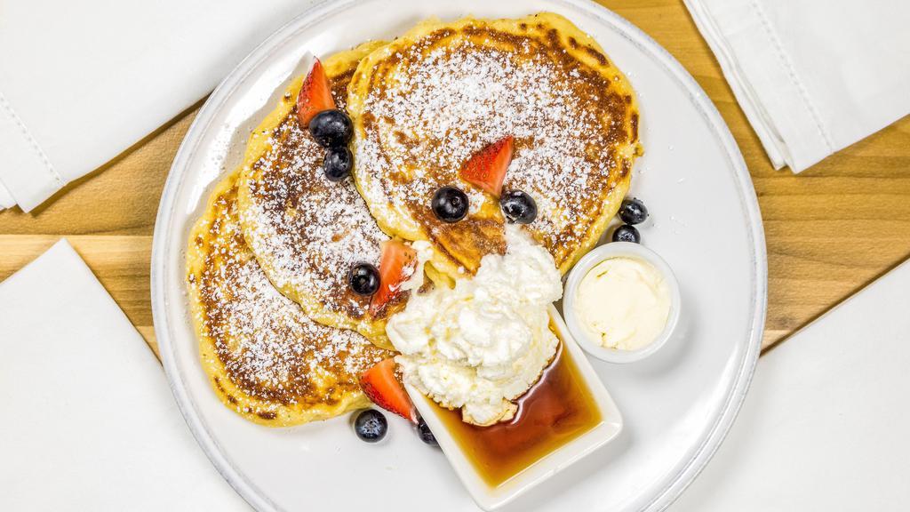 Classic Buttermilk Pancakes · Three jumbo buttermilk pancakes served with warm maple syrup, powdered sugar, salted butter topped with house whipped cream.