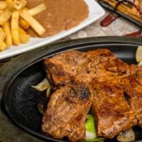 T-Bone Steak · Served with French fries, rice, refried beans and side salad / papas fritas servido con arro...