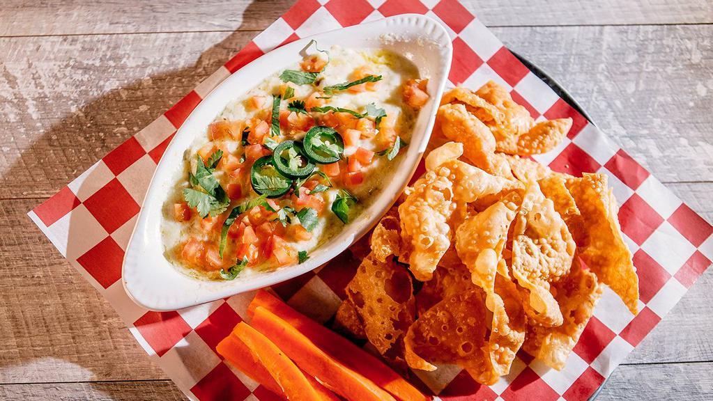 Artichoke Jalapeño Dip · Creamy, slightly spicy dip with artichokes and jalapeños, topped with tomatoes, jalapeño slices and cilantro – served with wonton chips and carrots.