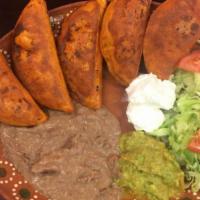 Enchiladas Potosinas · Served with refried bean, iceberg salad, guacamole and sour cream.