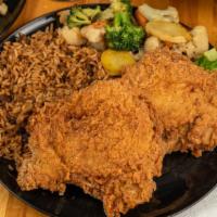 Pork Chops · Two pork chops, blackened or fried, served with dirty rice and mixed vegetables.