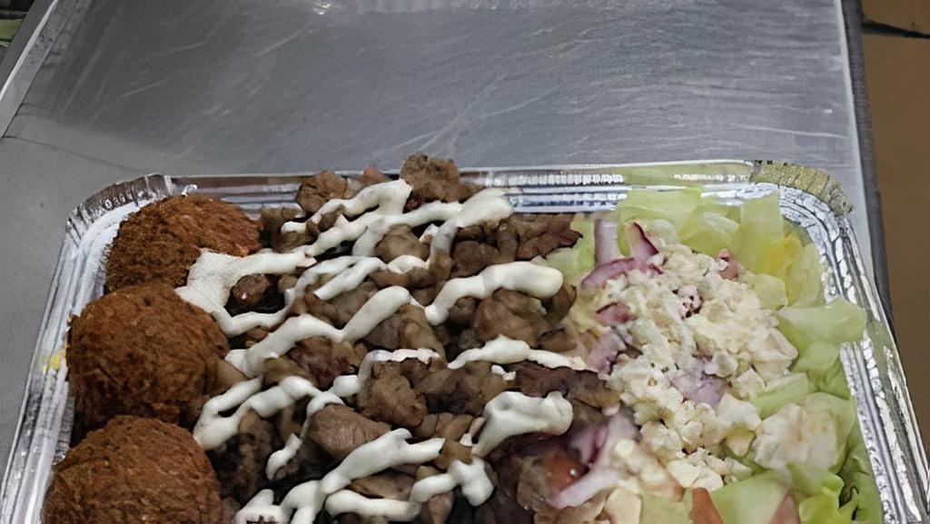 Falafel & Gyro Over Rice · Three pieces of falafel, lamb, basmati rice, lettuce, tomatoes, cucumbers, red onions, pickles, feta cheese, white (tzatziki) sauce, and hot (spicy) sauce.