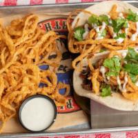 Brisket Tacos · Soft flour tortilla, copped prime brisket with deep fried onion strings drizzled with ranch'...
