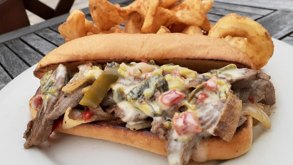 Texas Cheese Steak Sandwich · Grilled Peppers, Grilled Onions with Thinly sliced Skirt Steak with Poblano Queso served on a Hoagie Bun.